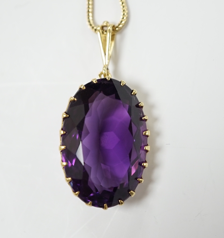 A yellow metal mounted single stone oval cut amethyst set pendant, 35mm, on a yellow metal chain, 48cm, gross weight 10.7 grams